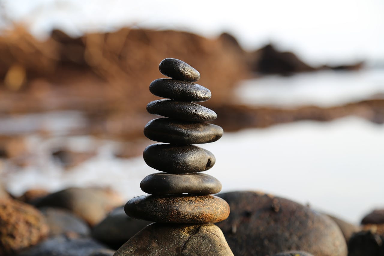 services-01 A stack of smooth stones artfully balanced by a waterside, evoking tranquility and zen.