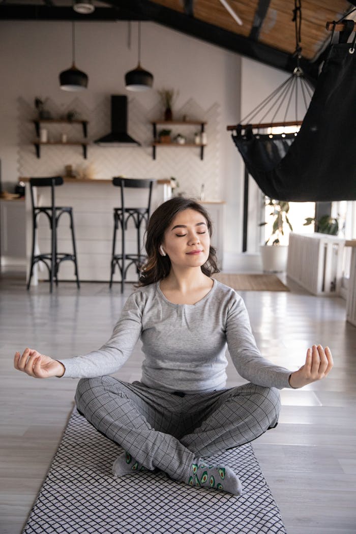 contact-img A woman meditates peacefully on a yoga mat indoors, promoting mindfulness and relaxation.