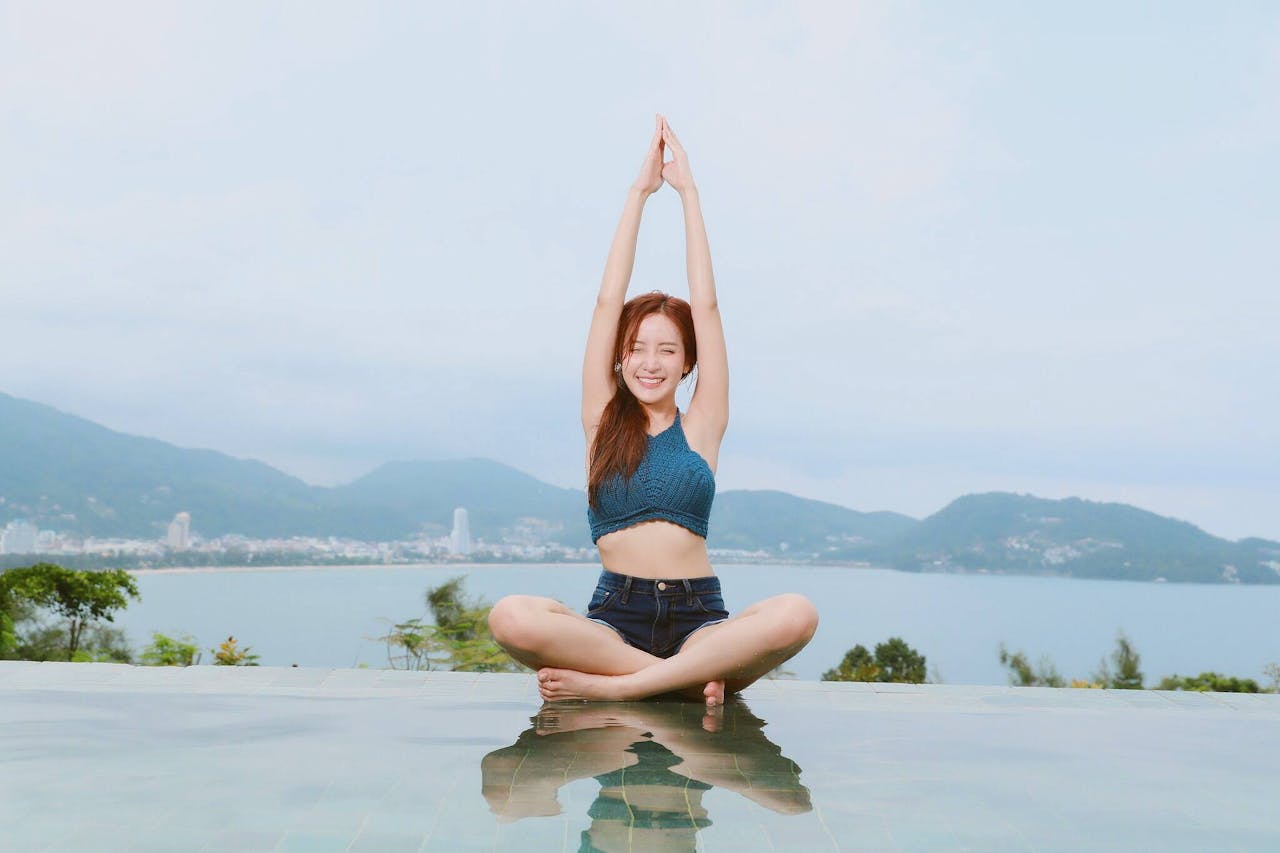 services-02 Young woman doing yoga by a scenic waterfront, enjoying a serene landscape.